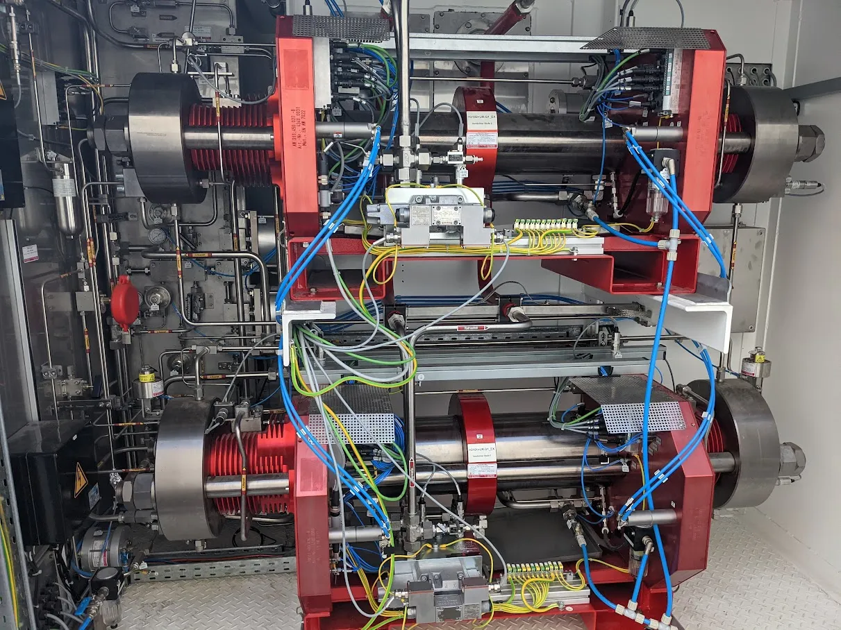 Two-stage hydraulically driven piston compressor with instrumentation and sensor cabling