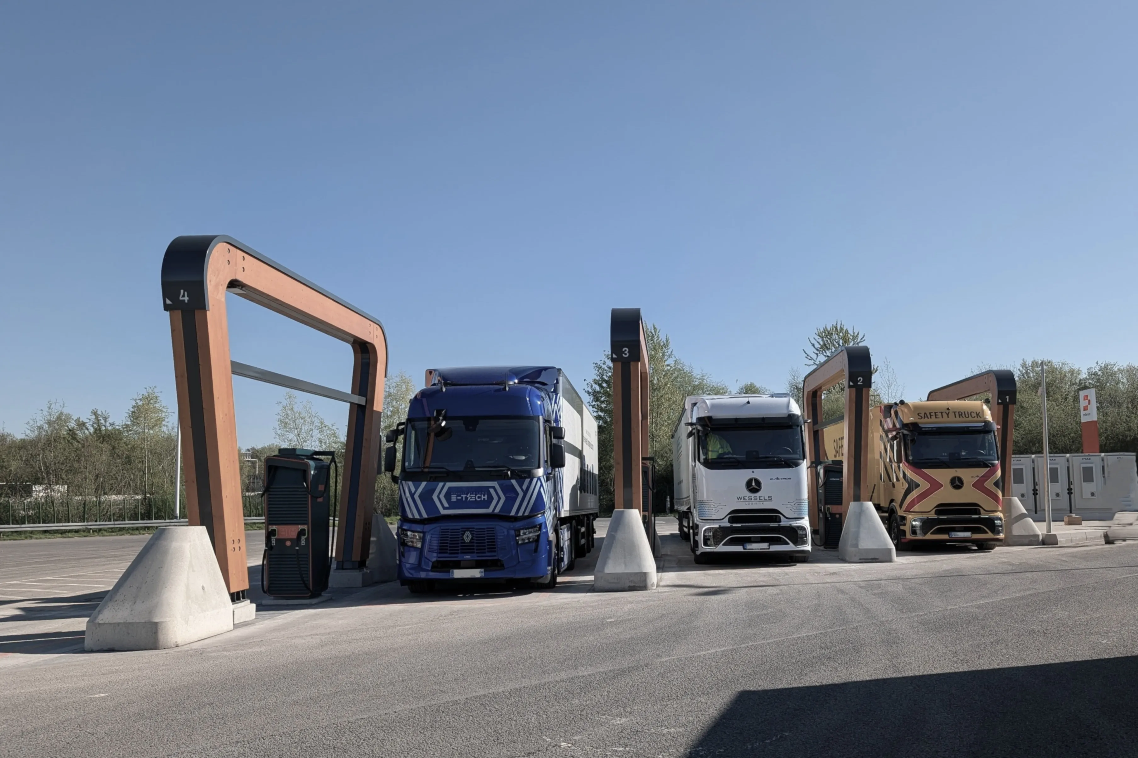 Row of electric trucks from several manufacturers at a charging site